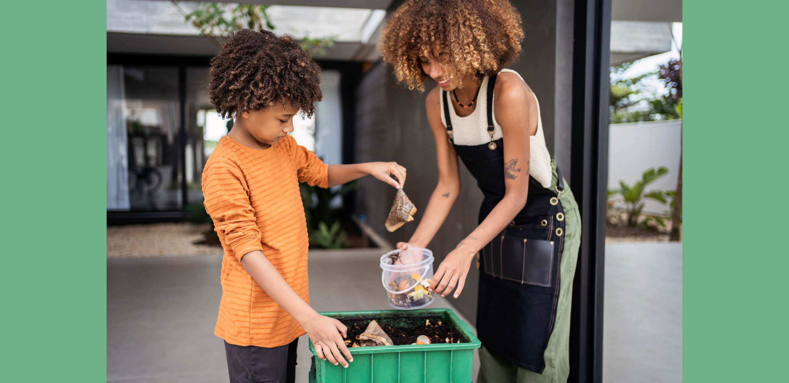 A young woman and male child adding food scraps to a compost bucket