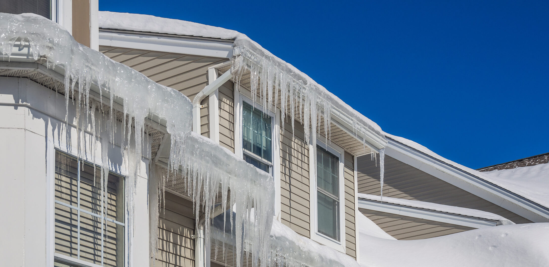Ice dams with icicles overflowing the gutters on a house