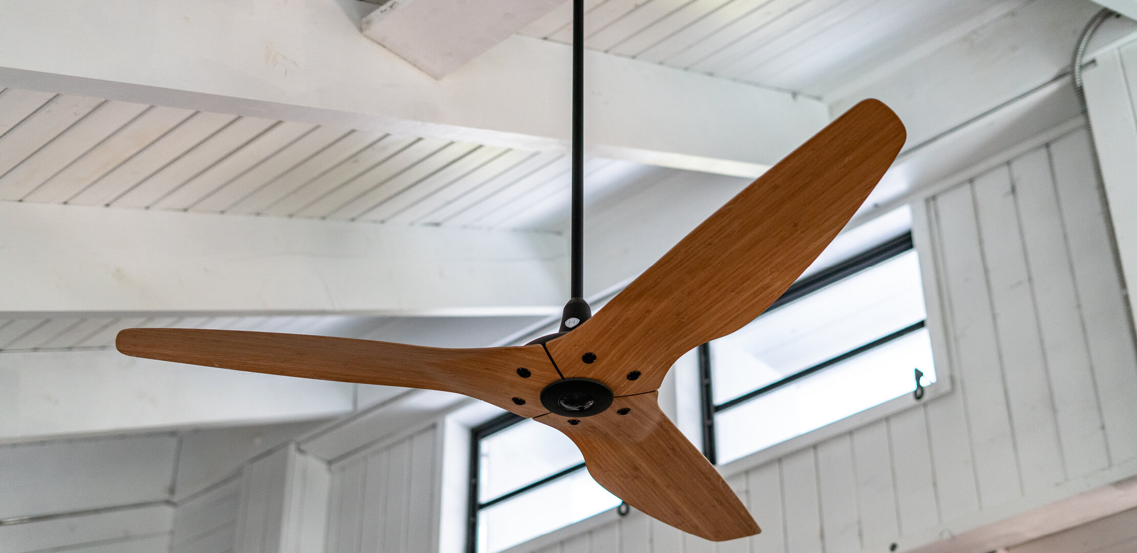 A modern wooden ceiling fan with three blades