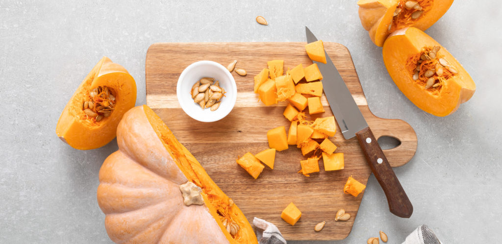 A cutting board with a winter squash and knife