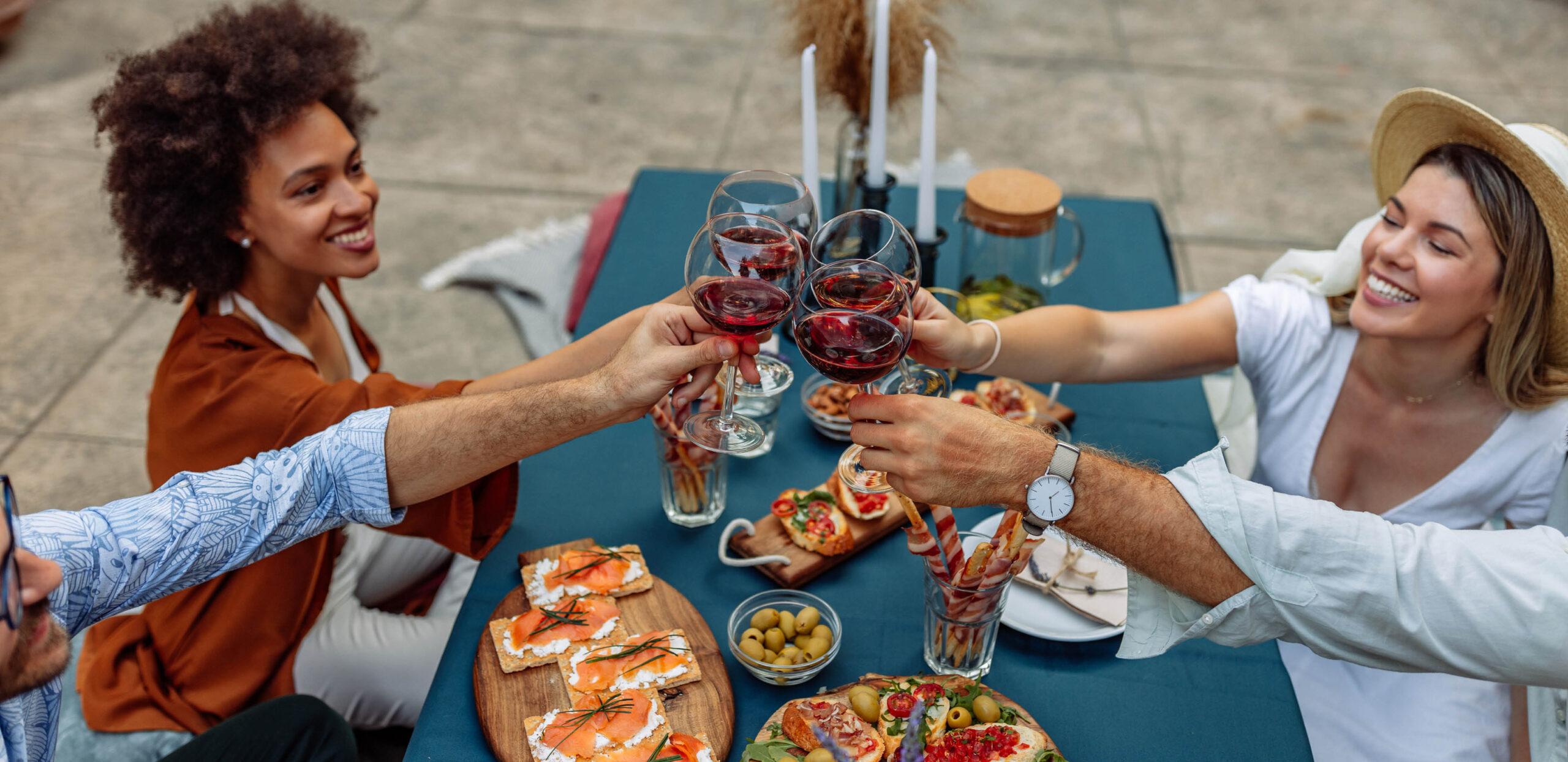 Two couples enjoying red wine and sophisticated hors d'ouevres at an outdoor table during summer