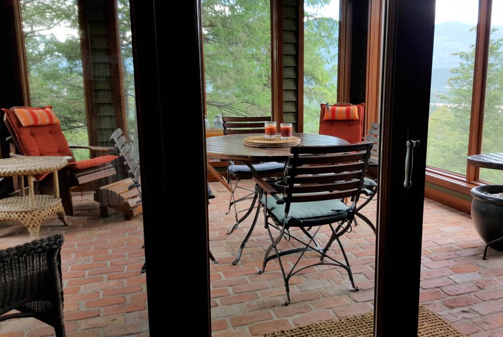 A screened in porch with brick floors and a comfortable seating area around a table