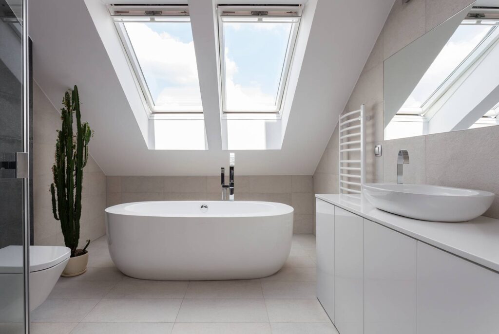 A modern, white bathroom which is brightly lit by two large skylights