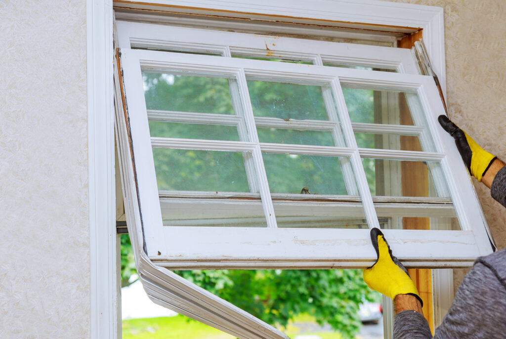 A handyman removing an old window so that it can be repaired