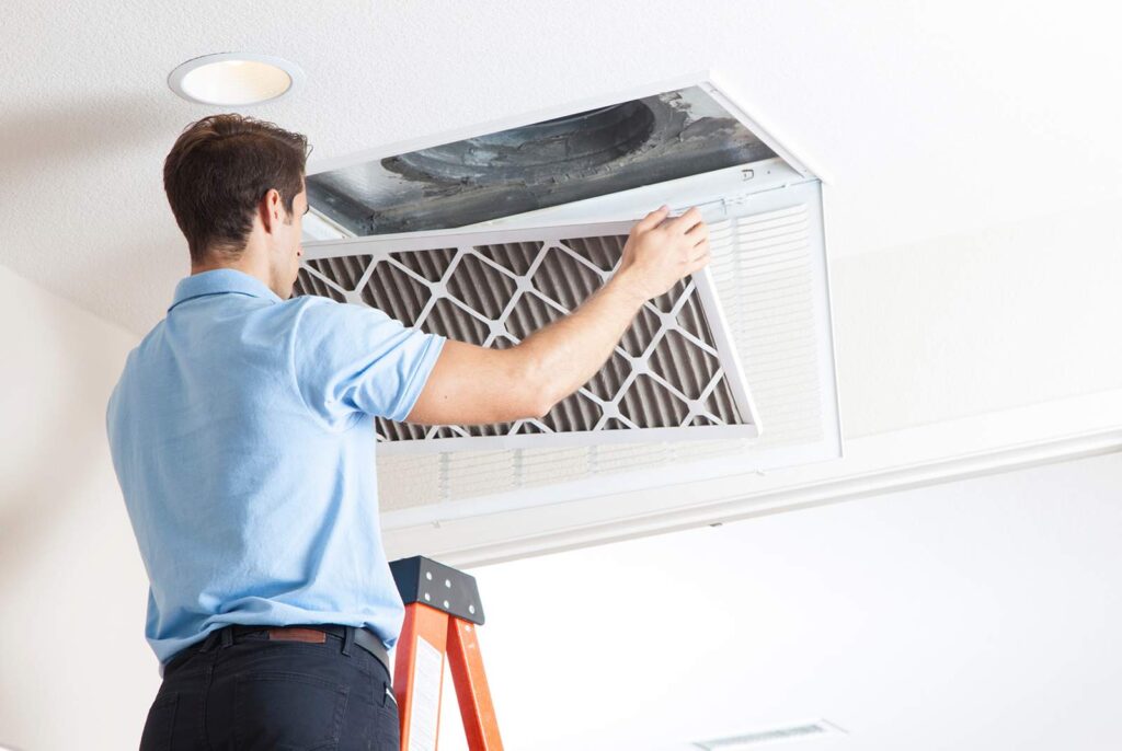 Handy Man cleaning an air duct and installing a new filter