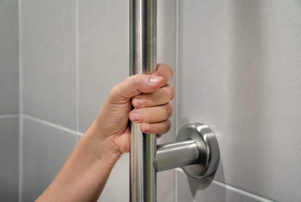 close up of woman's hand gripping a grab bar in the bathroom shower