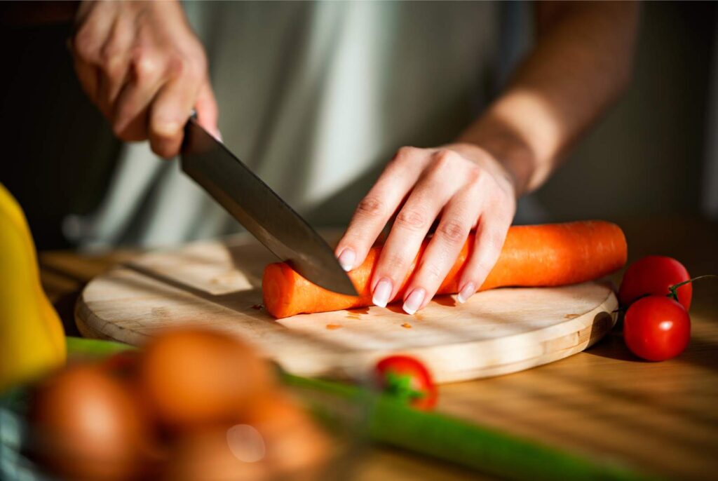 Woman chopping carrots with a sharp chef's knife