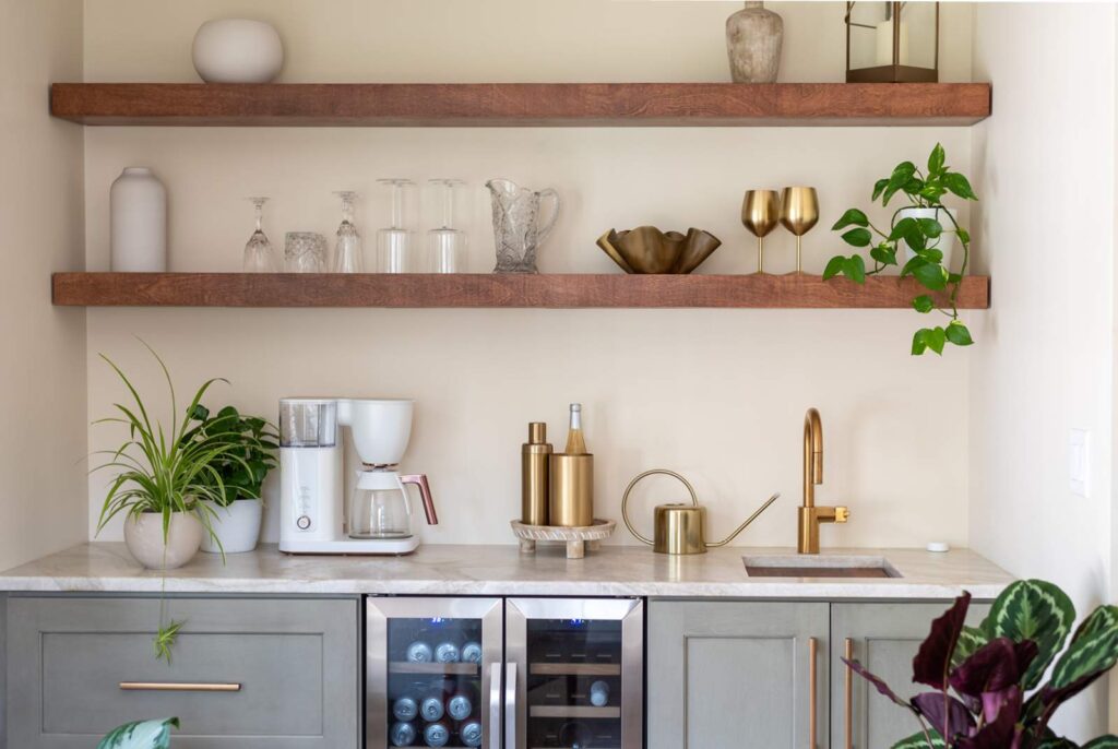 Contemporary beverage center with a built in under counter fridge, sink, cabinets and wood open shelving.