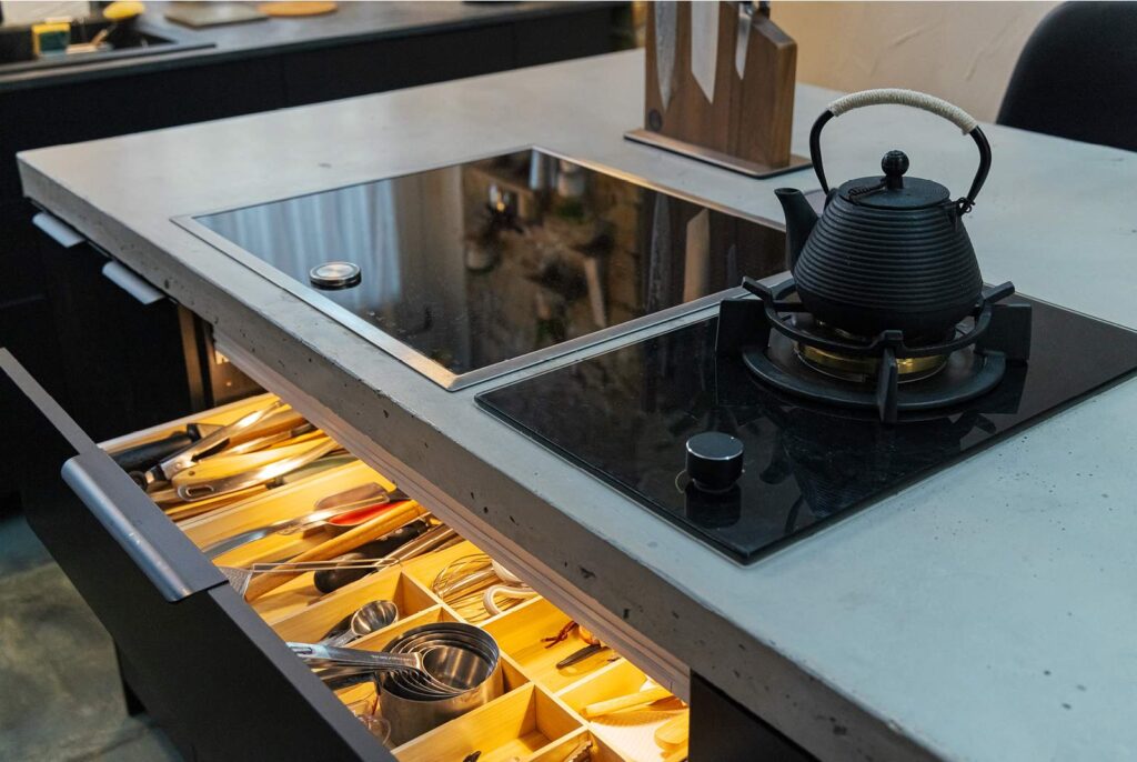 remodeled kitchen with an induction cook top and a gas single burner cook top with the cook top station drawer open showing cooking utensils