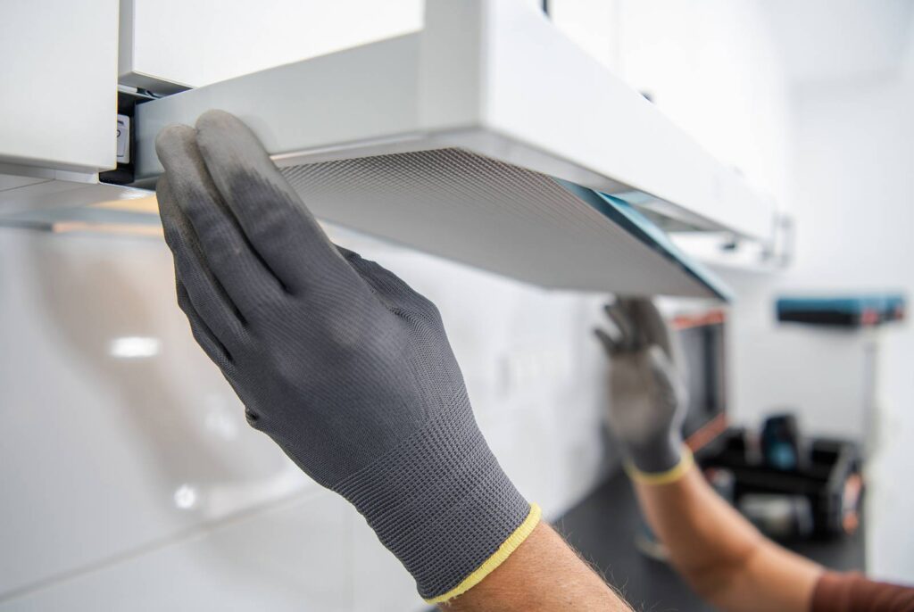 Closeup shot of a person wearing protective gloves cleaning a range hood