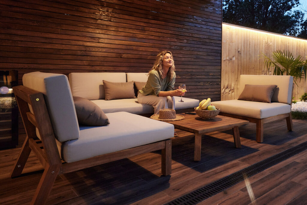 A woman enjoying her teak wood furniture on her wooden deck